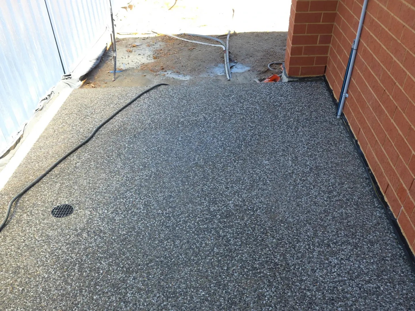 Exposed aggregate concrete path beside a brick home in Clarence Gardens, with a drainage grate set in