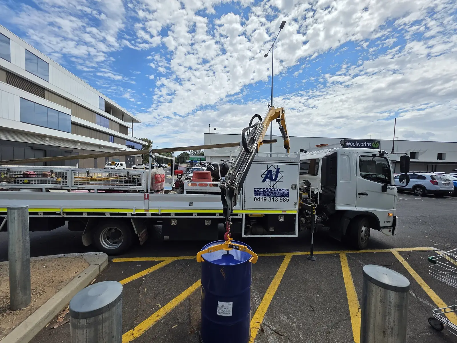 A and J Contractors crane truck lifting a steel drum with a drum clamp during a drum collection in Adelaide