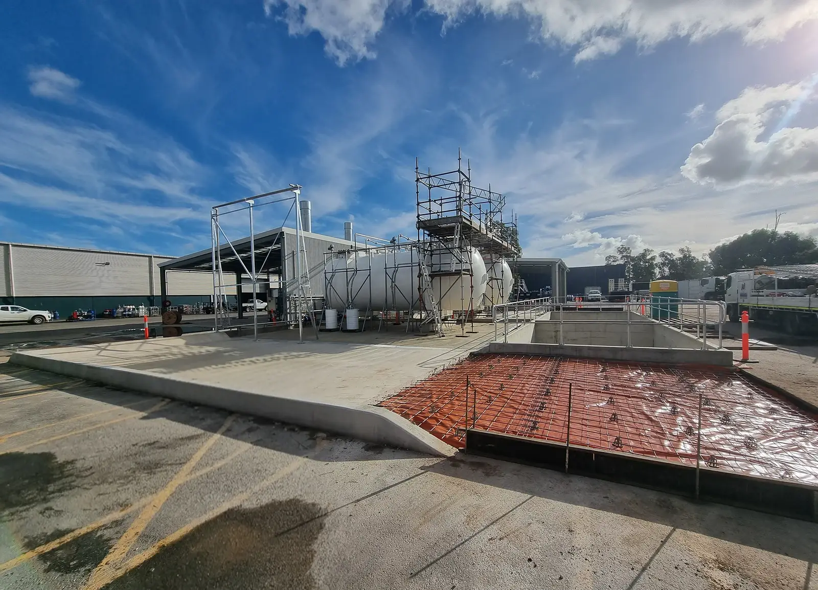 Concrete bund walls and upstands around industrial storage tanks, with reinforcement laid ready for the next pour